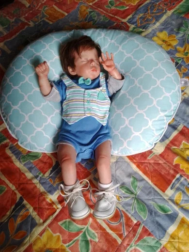 Lalka Reborn Lilli, realistyczne ciało z miękkiej tkaniny, ręcznie sadzone włosy i zamknięte oczy.