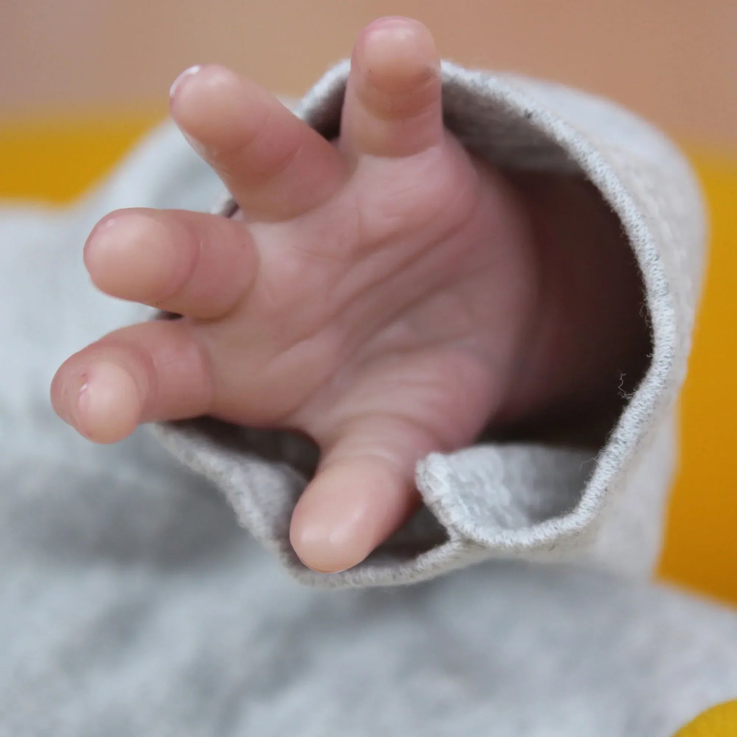 Lalka Reborn Lilli, realistyczne ciało z miękkiej tkaniny, ręcznie sadzone włosy i zamknięte oczy.